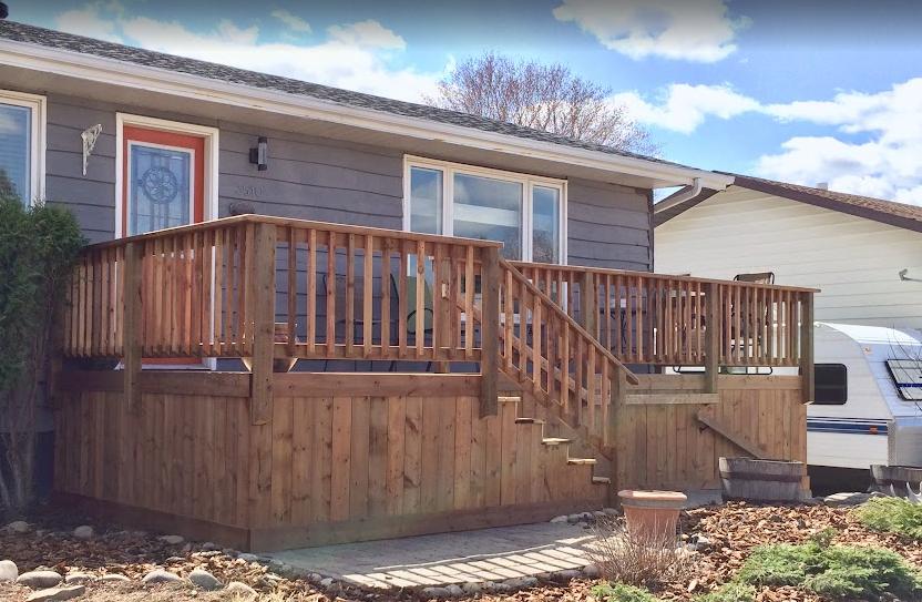Wooden deck with railings and stairs attached to a house.
