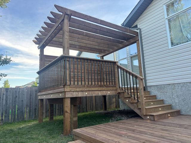 Wooden deck with stairs and pergola attached to house.