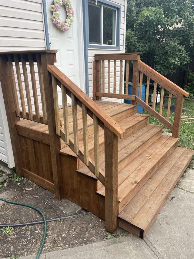 New wooden stairs and railing leading to a house door.