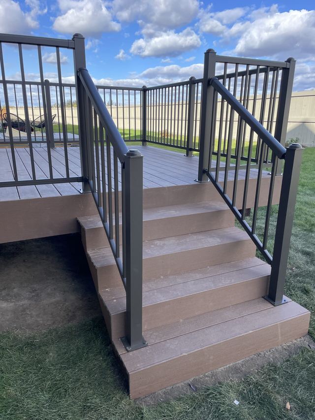 Outdoor stairs with black metal railing leading to a raised platform.