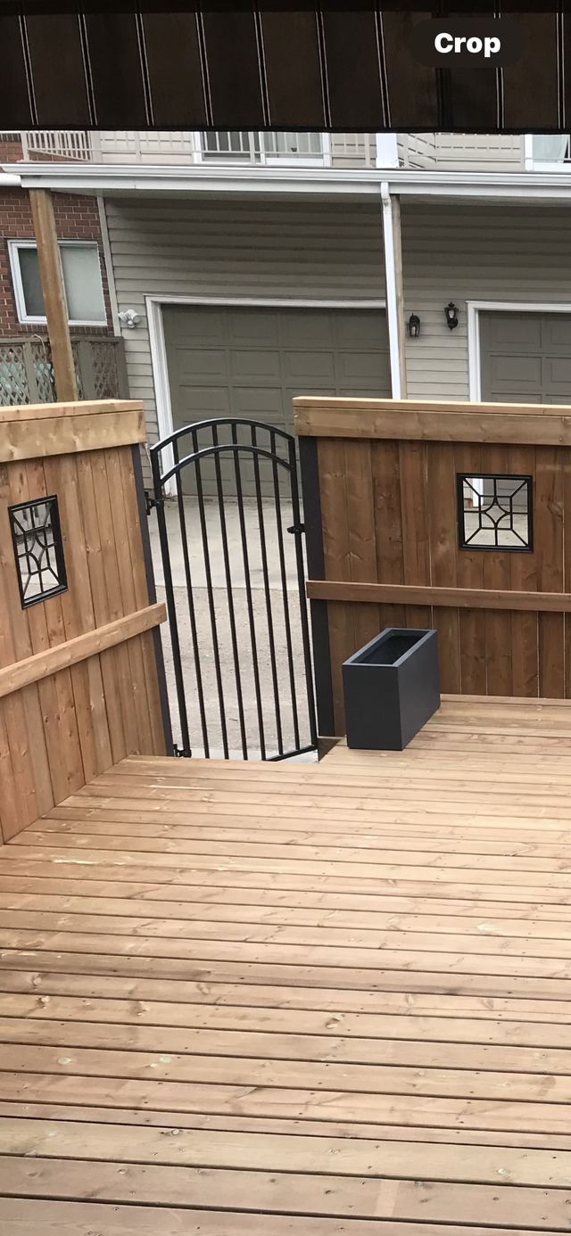 Wooden deck with decorative panels and a black metal gate.