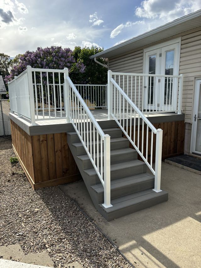 A small deck with white railings and stairs leading to a door.