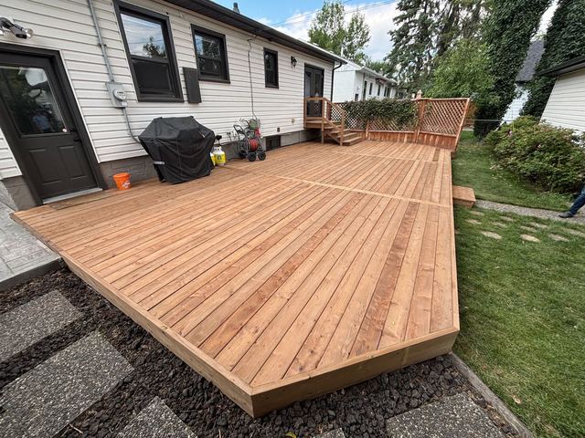 Newly built wooden deck attached to a white house with a grill.