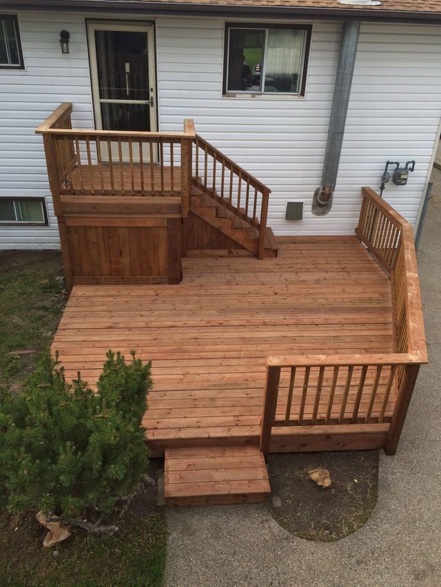 A wooden deck with steps and railings attached to a house.