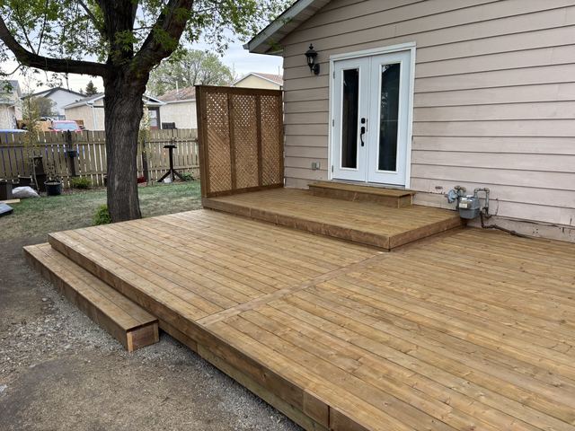 Newly constructed wooden deck with steps leading to a house door.