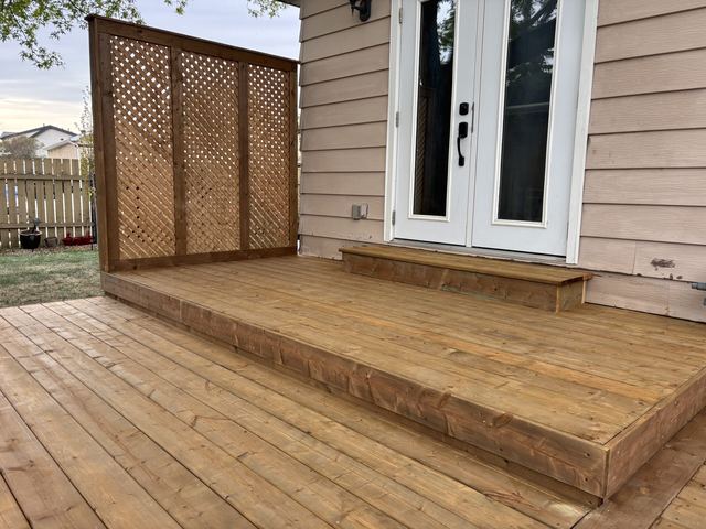 Wooden deck and steps leading to white double doors.