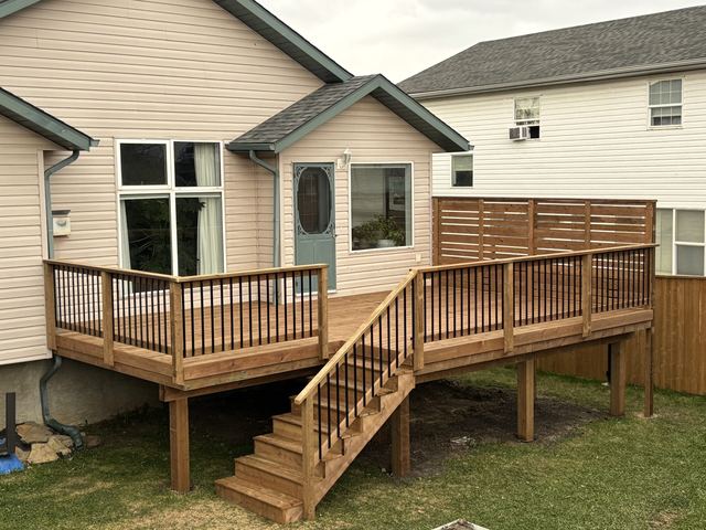 Wooden deck with railing and stairs attached to a beige house.