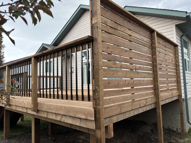 Wooden deck with metal railings attached to a house.