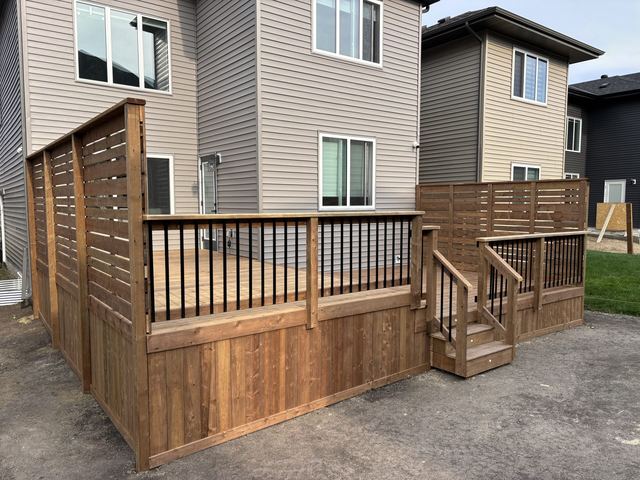 Newly built wooden fence with railing and small staircase in a residential area.