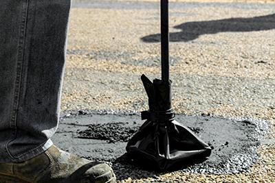 A person standing on a gravel surface with a black tripod base.
