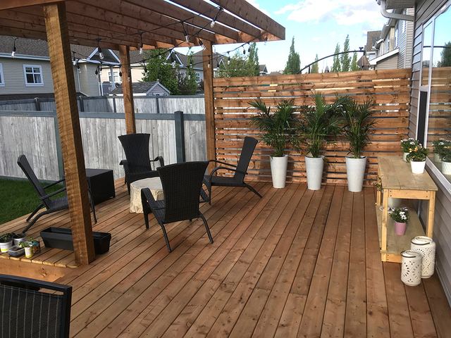 Wooden patio with chairs and potted plants.