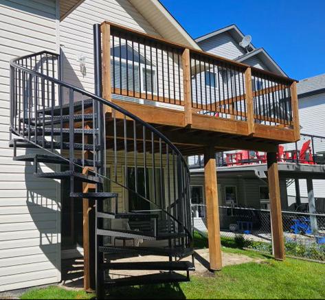 Spiral staircase leading to a wooden balcony on a house.