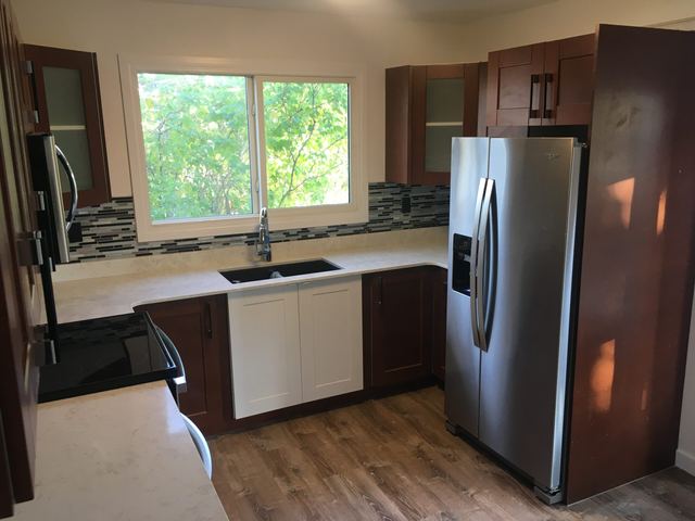 Modern kitchen with wooden cabinets and stainless steel fridge.