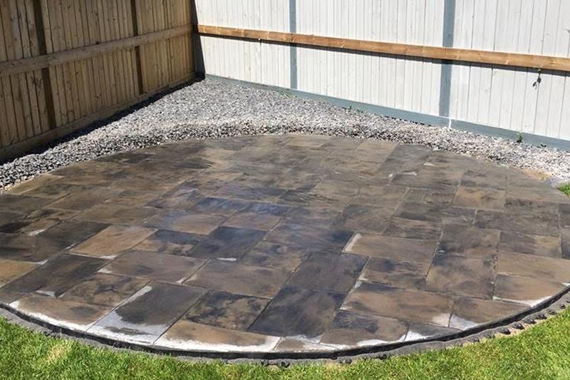 Newly paved stone patio with a gravel border in a backyard corner.