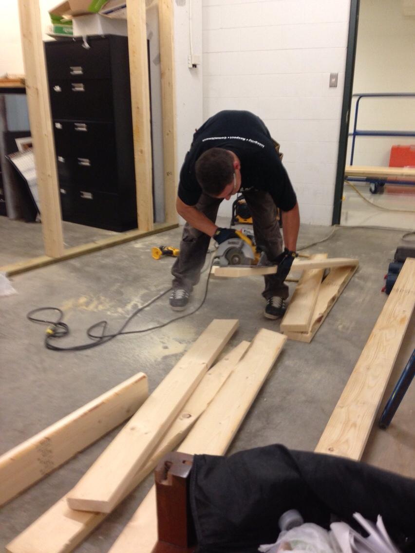 Man cutting wood planks indoors with a power saw.