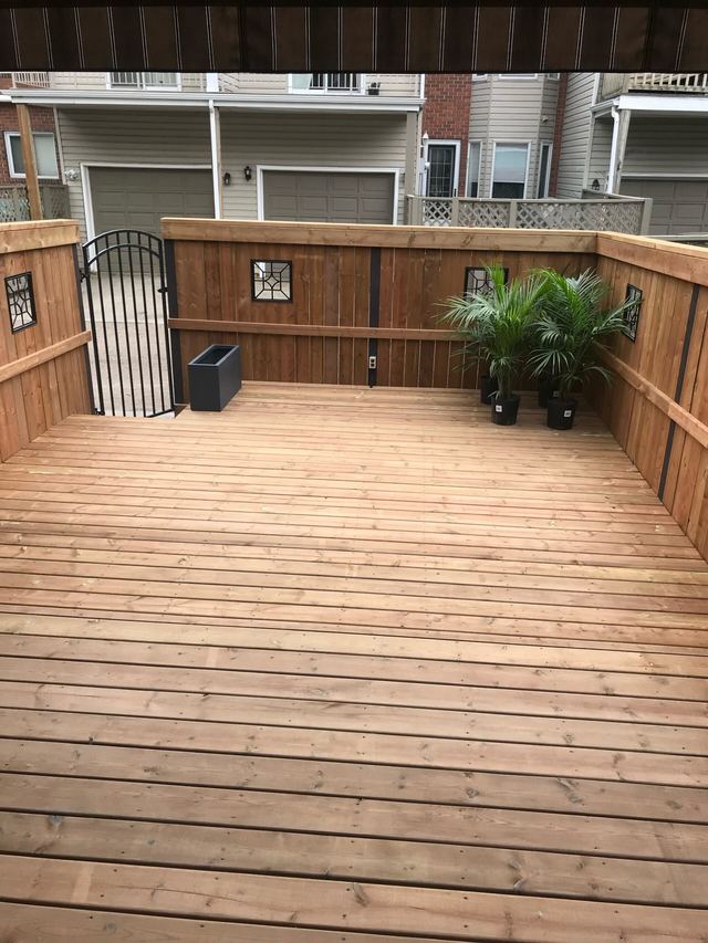 A clean wooden deck with potted plants and a grill.