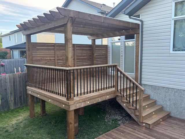 Wooden deck with pergola and stairs attached to a house.