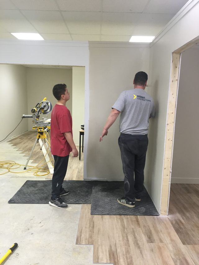 Two men working on flooring installation in a room.