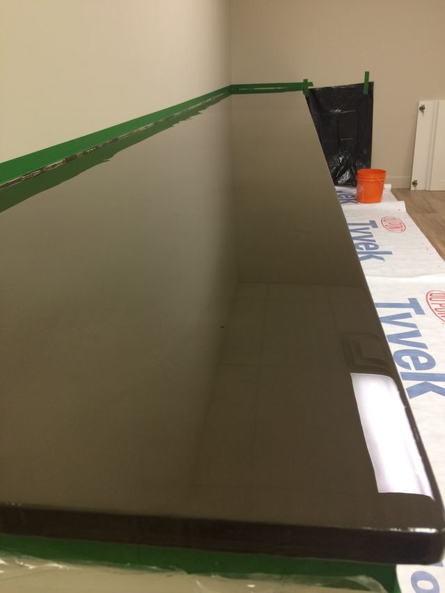 A shiny black rectangular panel resting on a table with some items around.