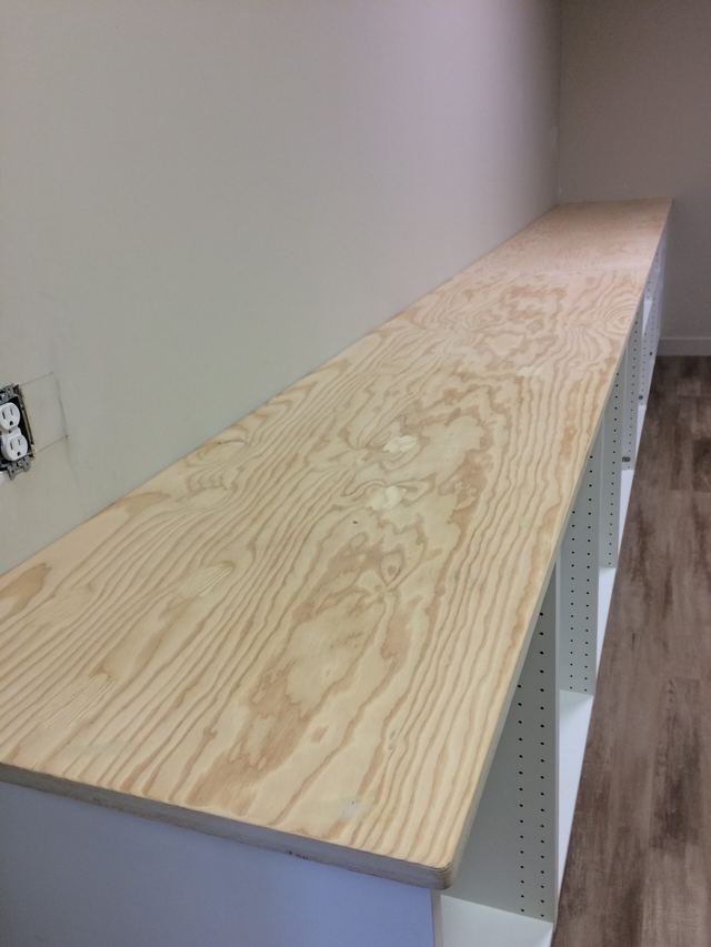 Long wooden shelf installed along a wall in a room.
