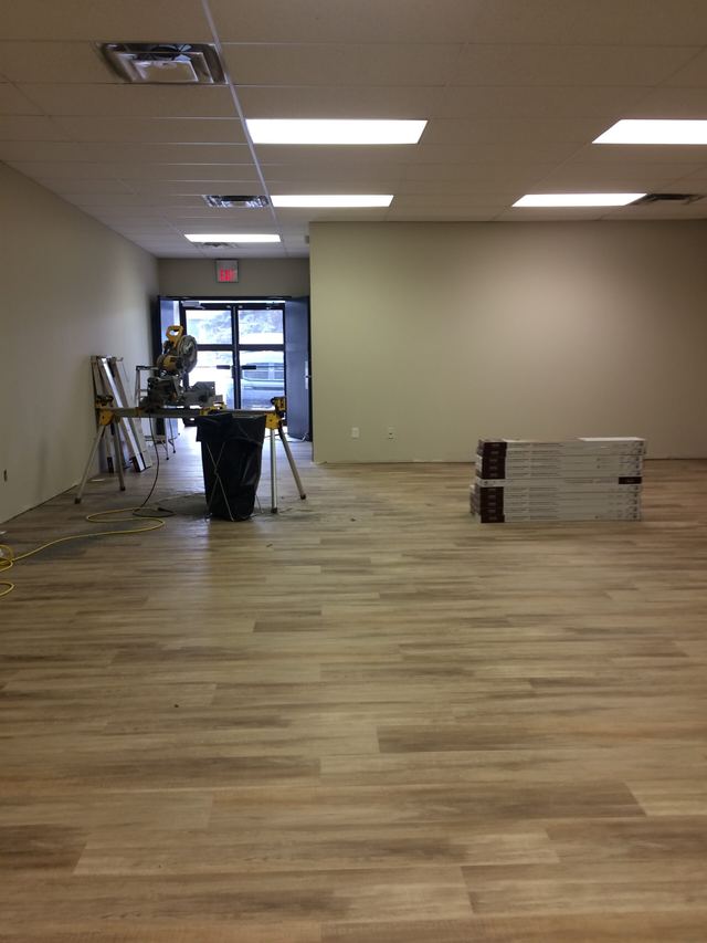 Empty room with new wooden flooring and minimal furniture.