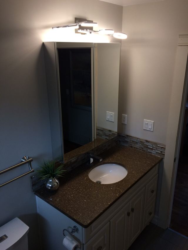 Modern bathroom vanity with granite countertop and round sink.
