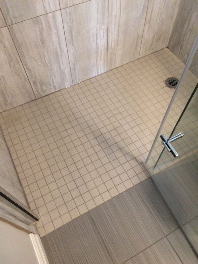 Glass shower door with visible water stains and a metal handle.