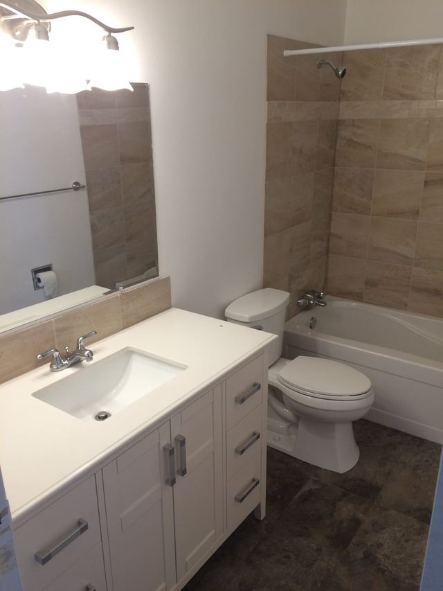 Modern bathroom with white vanity, toilet, and bathtub.