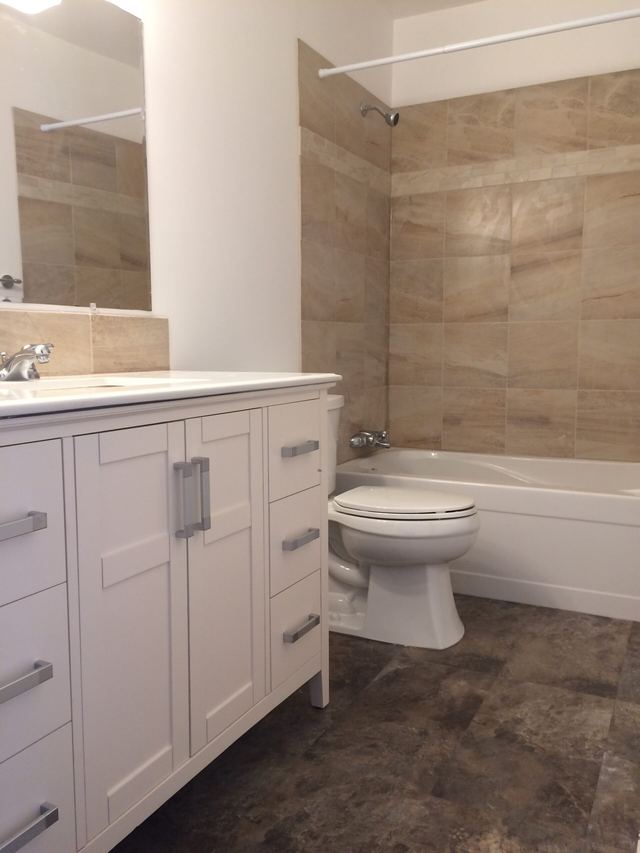 Modern bathroom with white cabinetry and stone tile walls.