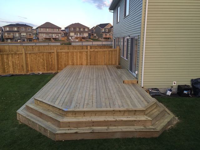 Newly built wooden deck with steps in a backyard.