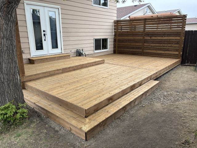 Newly built wooden deck attached to a house with steps.