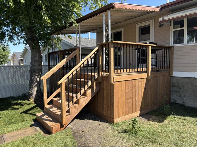 A wooden deck with stairs and railing beside a house.