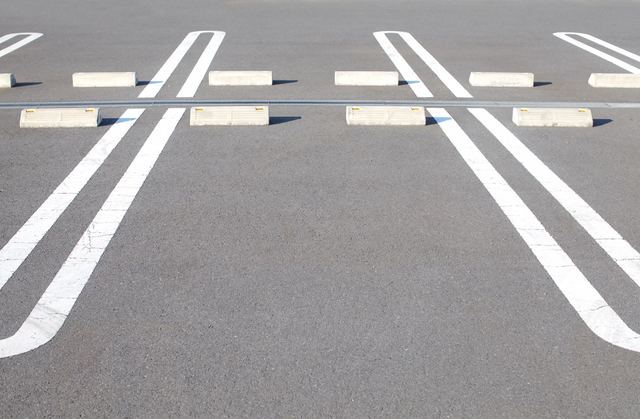 Empty parking spaces with wheel stops on an asphalt surface.