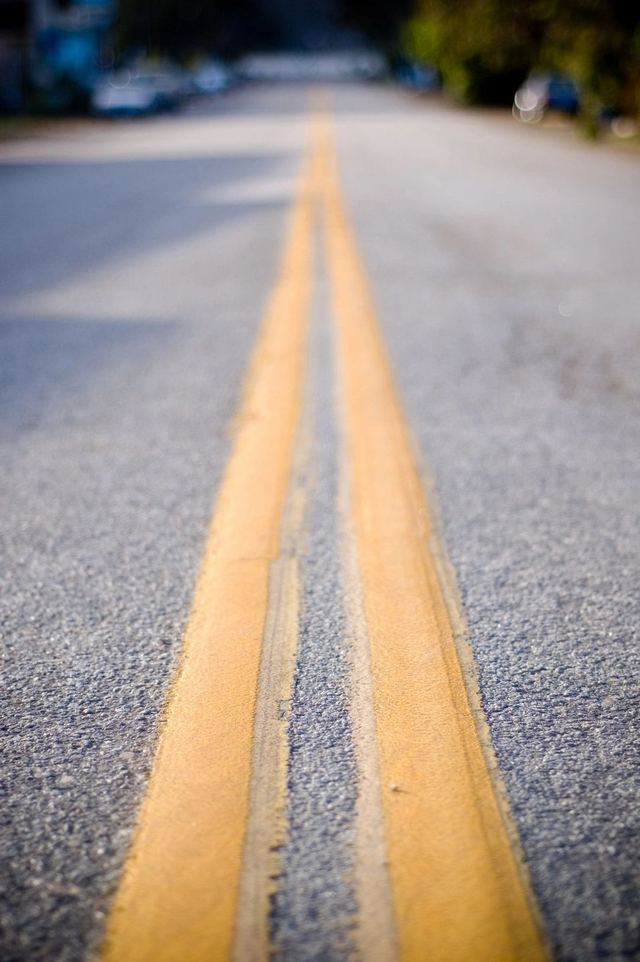 Close-up of double yellow road lines on asphalt.