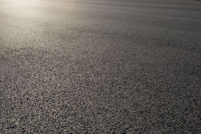 Close-up of a textured asphalt road surface under soft light.