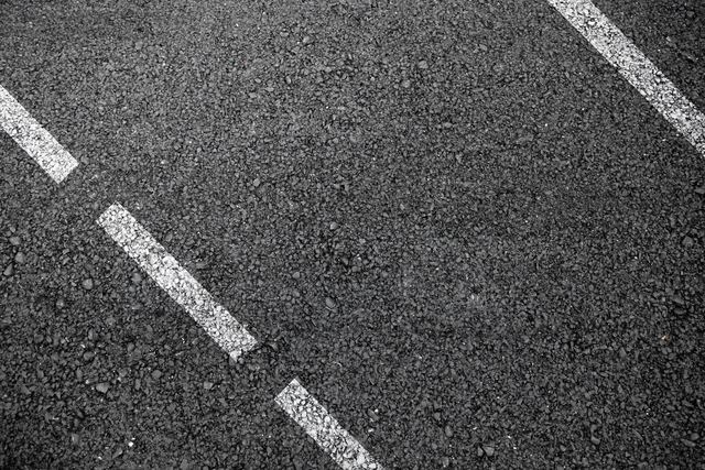 Close-up of asphalt road with white dashed line.