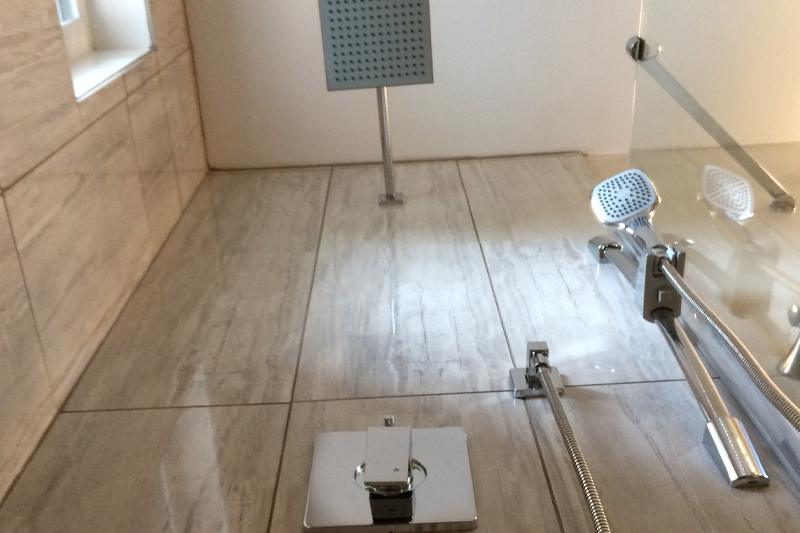 Modern shower setup with a square overhead showerhead and hand shower.